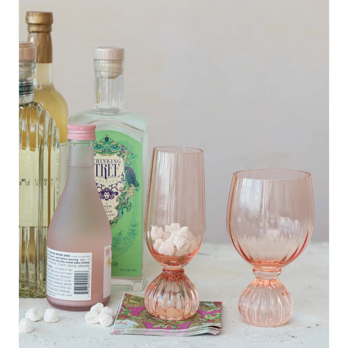 Collection of liquor bottles with pink ribbed wine glass and elegant glassware