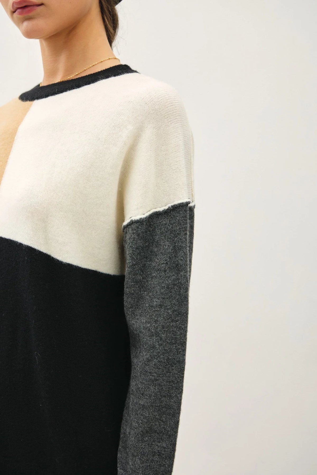 Color-blocked crew neck sweater in cream, black, and gray sections for stylish comfort