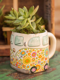 Colorful hand sculpted ceramic mug shaped like a hippie van with succulent plant inside rim