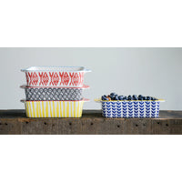 Colorful patterned ceramic baking dishes stacked, showcasing the Hand Stamped Stoneware Baker