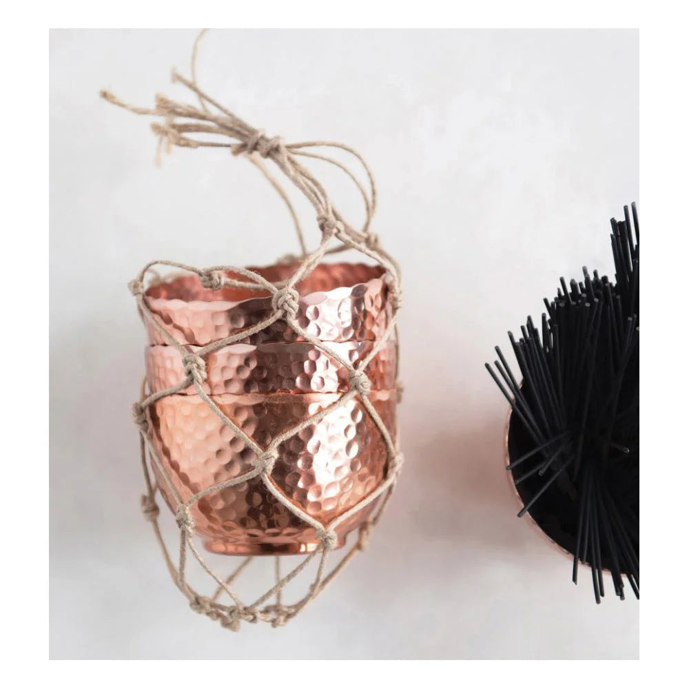 Copper-colored hammered metal cup in a macramé holder for boho decor lovers