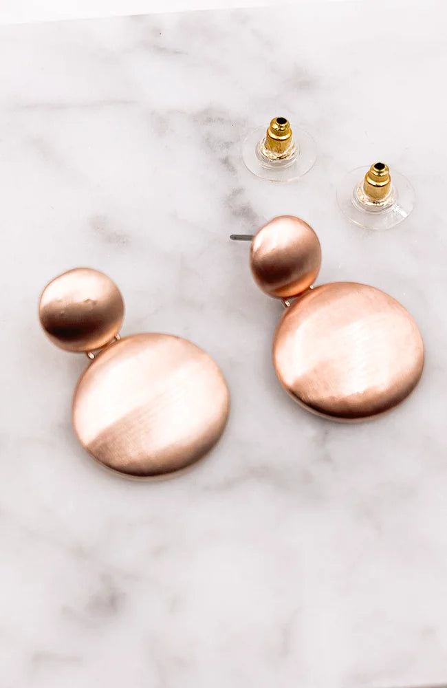 Rose Gold Round Drop Earrings elegantly displayed on a marble surface