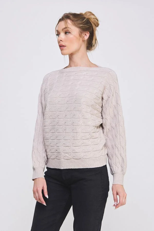 Cream-colored long sleeve cable knit sweater featuring a round neckline and textured design