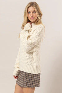 Cream-colored high neck cable knit sweater, a perfect addition to women’s boho chic clothing