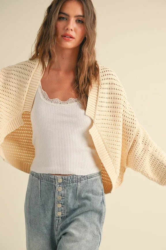 Cream-colored chunky knit cardigan over lace tank top, perfect for women’s boho chic clothing