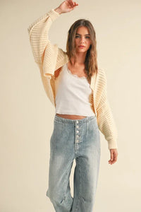 Cream-colored chunky knit cardigan styled with light wash jeans and a tank top, ideal for women’s boho chic clothing