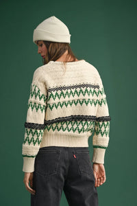 Cream-colored Aztec pattern sweater with geometric design worn with a white beanie