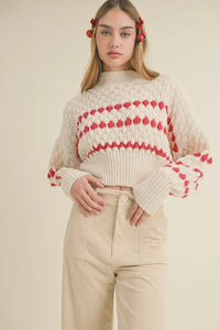 Cream-colored color popped sweater with red heart patterns and puffed sleeves