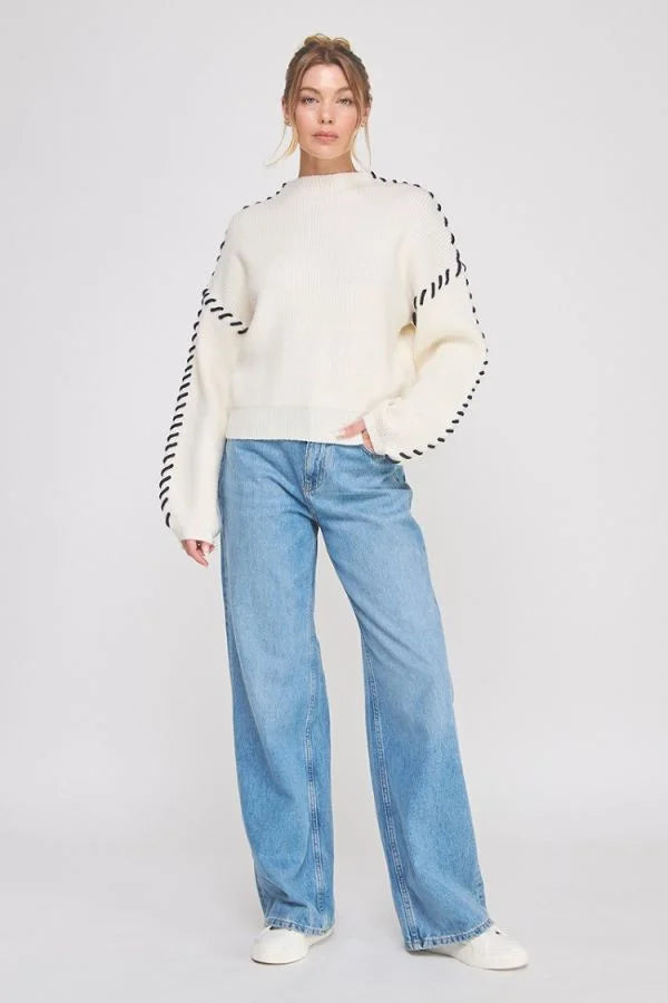 Cream-colored Lofty Mock Neck Sweater with black zigzag sleeve trim