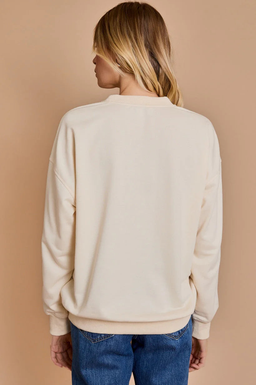 Cream-colored knit sweater with ribbed cuffs styled with blue jeans from Shop Daisy