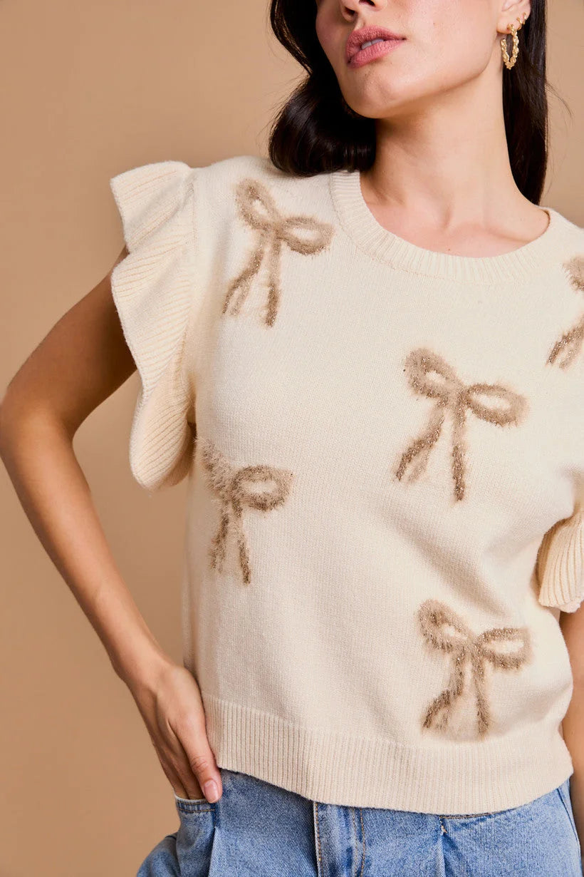 Cream-colored knit sweater with bows and ruffled shoulders, ideal for women’s boho chic clothing