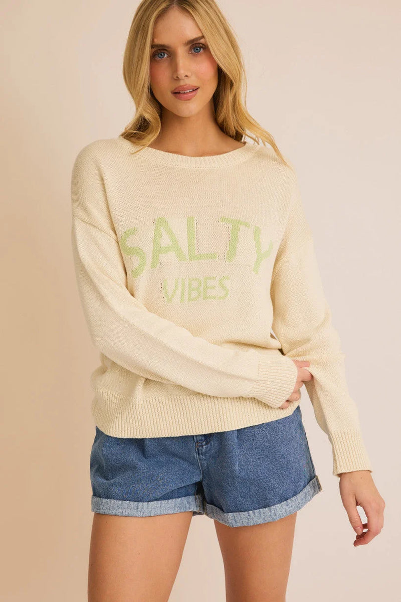 Cream-colored knit sweater with green text styled with denim shorts for a salty vibes light look