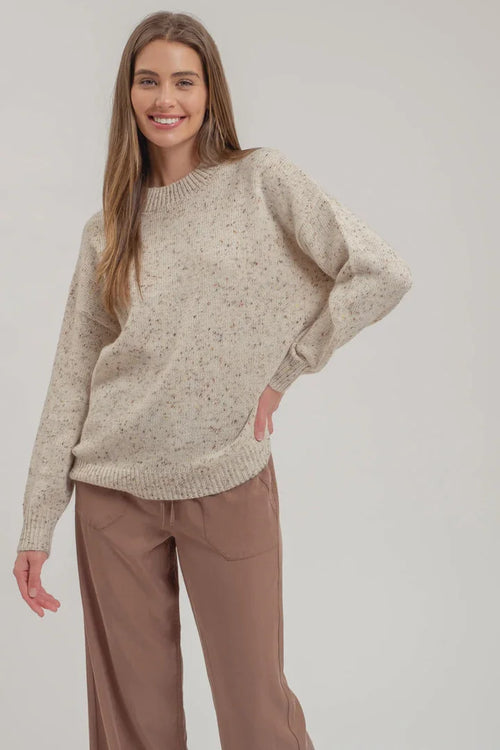 Cream-colored speckle knit long sleeve sweater with ribbed edges and a stylish pattern