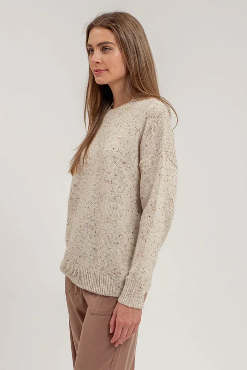 Cream-colored speckle knit long sleeve sweater worn by a person with long brown hair