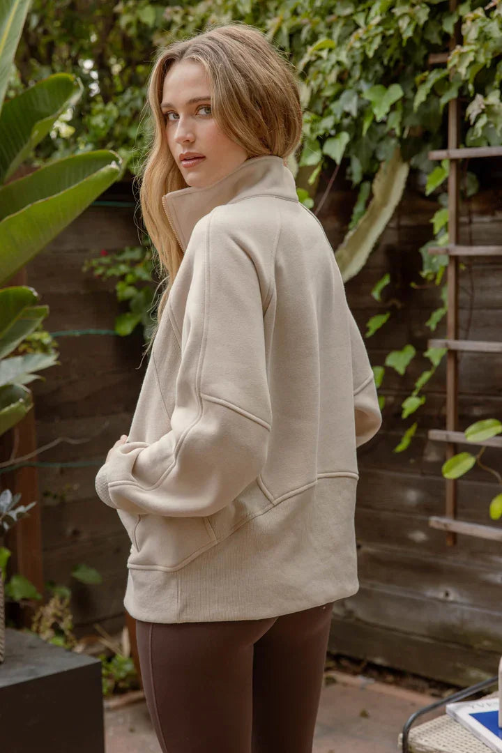 Cream-colored oversized half zip long sleeve knit top worn by a person