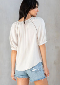 Cream-colored floral puff sleeve blouse with gathered neckline and puff sleeve button front design