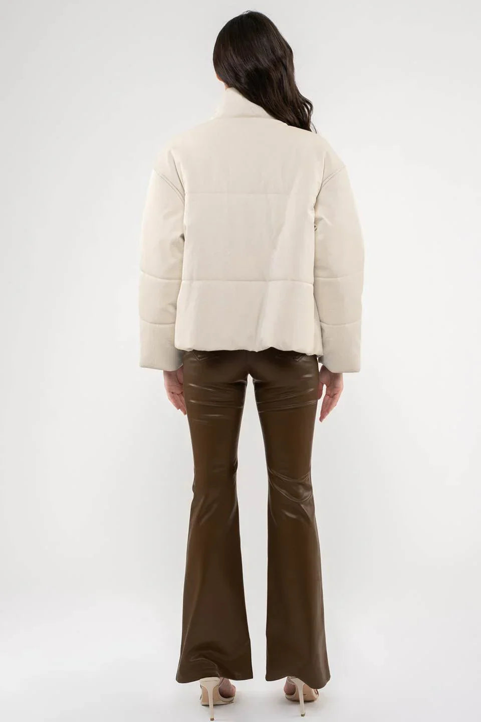 Cream-colored puffer jacket styled with brown flared pants for a chic faux leather look