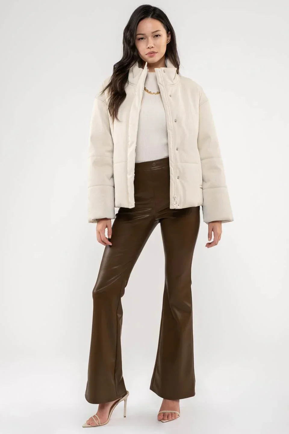 Cream-colored puffer jacket with high collar, a stylish turtle neck faux leather jacket