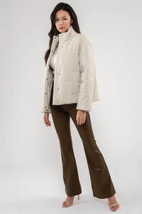 Cream-colored puffer jacket with brown flared pants and turtle neck faux leather jacket