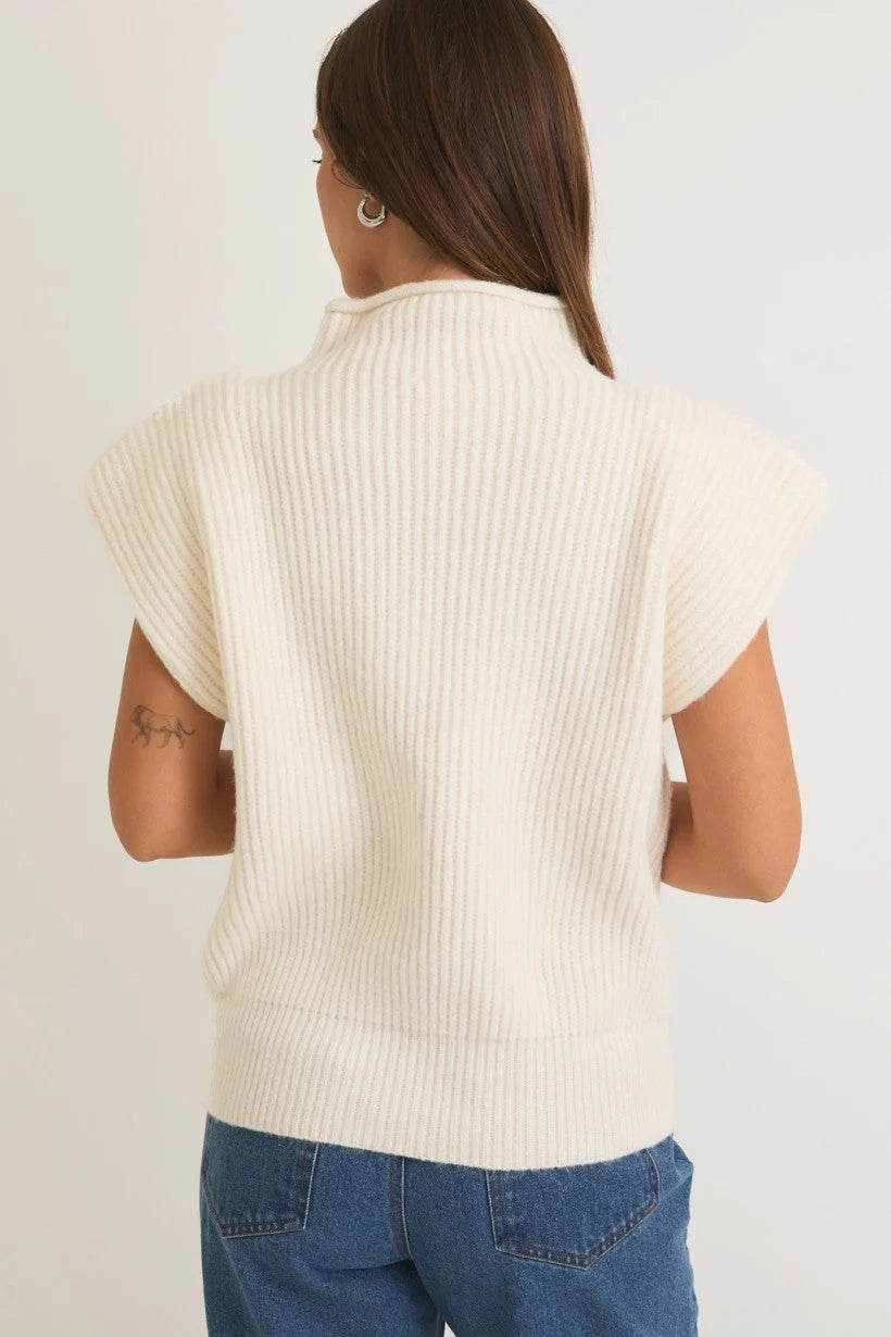 Cream-colored mock neck power shoulder sweater worn by a person with long dark hair