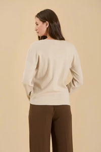 Cream-colored solid v neck seam knit sweater displayed on a person facing away from the camera