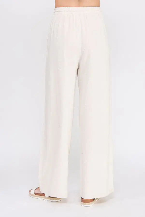 Cream-colored wide-leg embroidered linen pants with scallop trim for elegant style