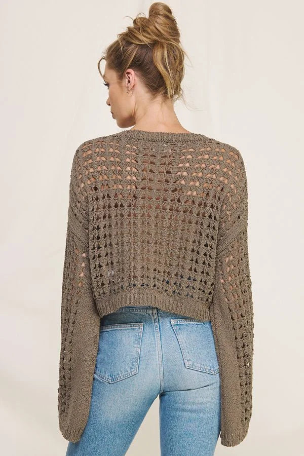 Cropped brown long flared sleeve open weave sweater styled over blue jeans