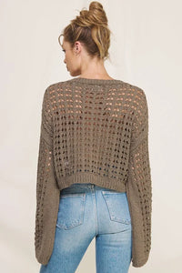 Cropped brown long flared sleeve open weave sweater styled over blue jeans