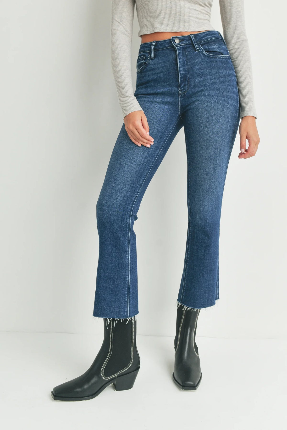 Cropped flare denim jeans with raw hem edges paired with black western boots