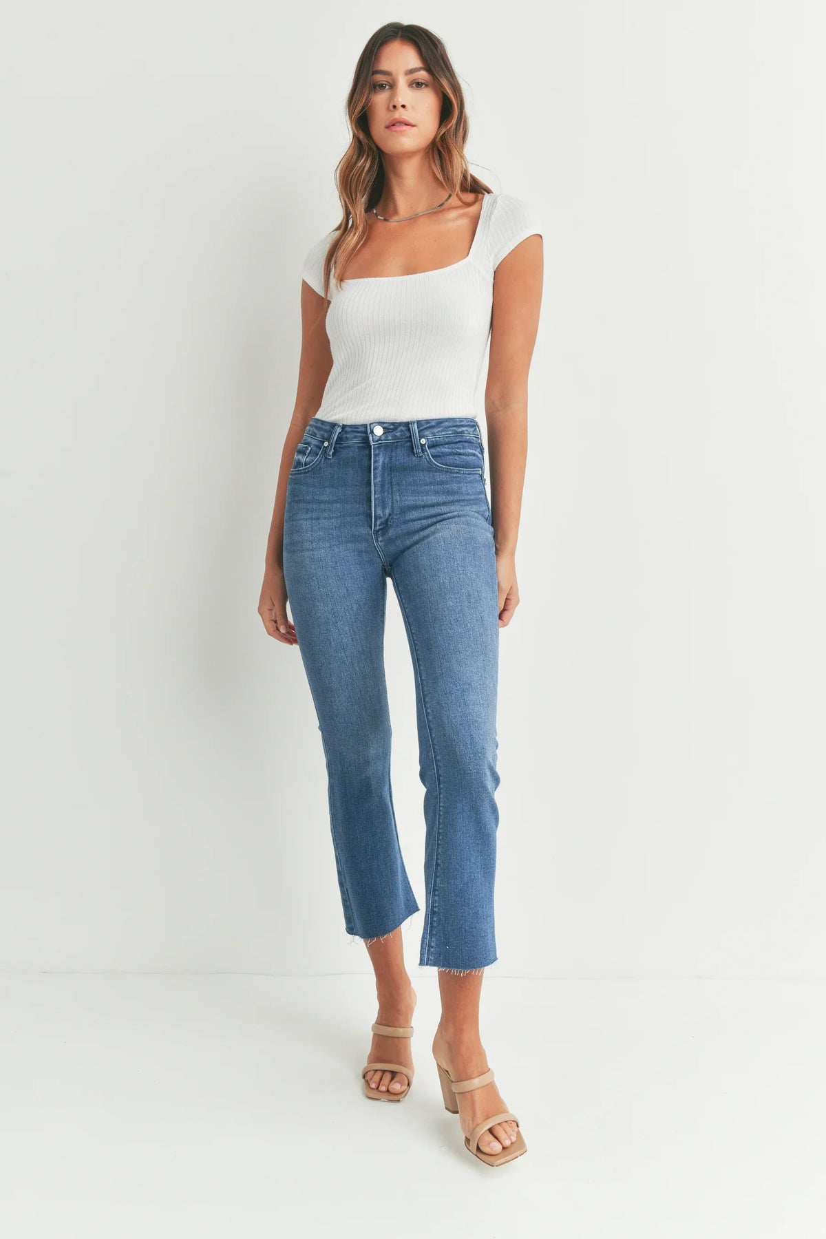 Cropped flare denim styled with a white bodysuit and beige sandals for a chic look