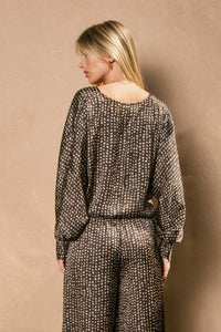 Dark-colored long-sleeved jumpsuit with light dotted pattern, perfect for women’s boho chic clothing from Shop Daisy