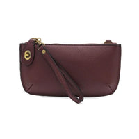 Dark red leather clutch with wristlet strap and gold hardware, perfect for women’s boho chic clothing at Shop Daisy