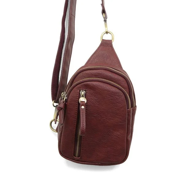 Dark red leather sling bag with multiple zippered compartments and brass hardware