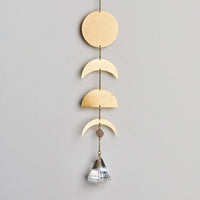 Decorative wall hanging of wooden moon phases with a crystal pendant, perfect for boho decor