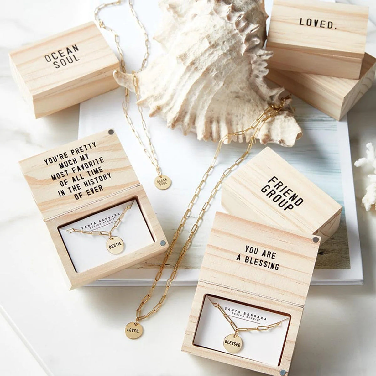 Delicate gold link necklaces in wooden boxes with inspirational messages from Shop Daisy