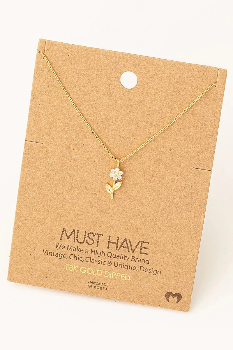 Delicate gold-toned Rhinestone Flower Charm Necklace displayed on kraft paper card