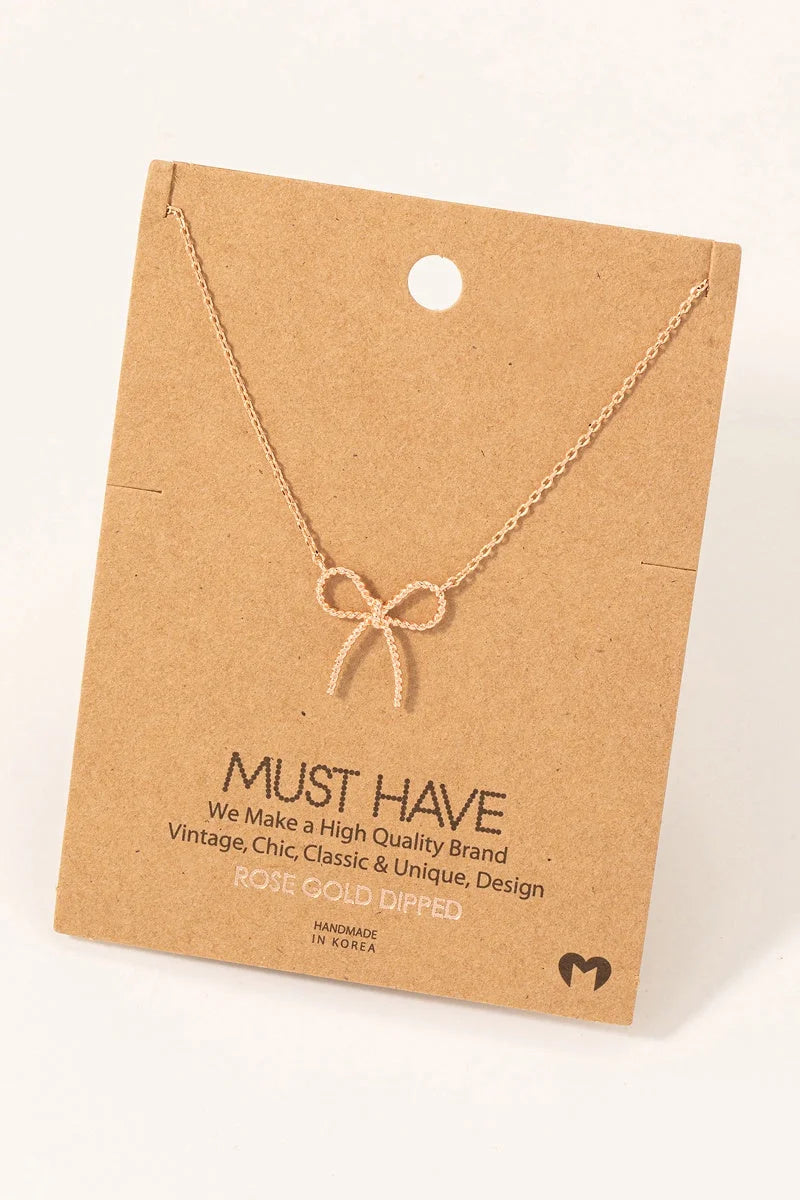 Delicate gold-toned Textured Bow Pendant Necklace on a cardboard jewelry card