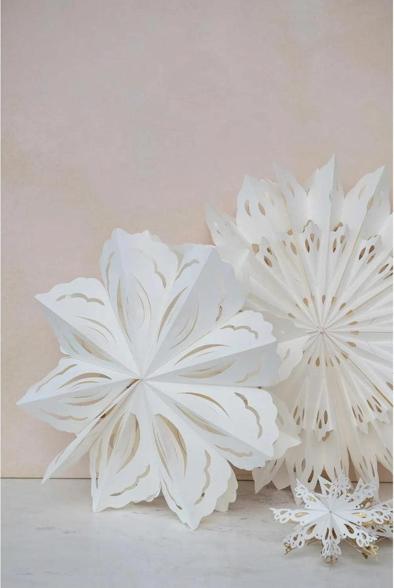 Delicate white paper snowflake ornament showcasing intricate cut-out patterns for holiday decor