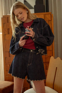 Denim jacket with scalloped hem and distressed details, dark blue material.