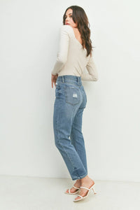 Distressed light-wash girlfriend straight leg jeans styled with a cream top and white heels