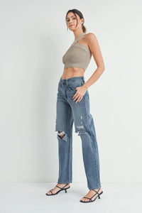 Distressed baggy skater jeans with ripped knees paired with a beige crop top