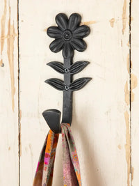 Flower-shaped iron wall hook elegantly holding a scarf, ideal for home decor solutions
