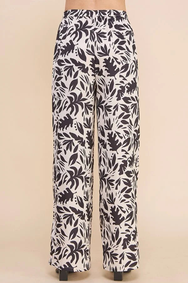 Flowy printed satin high waisted wide leg pants with black and white leaf print pattern