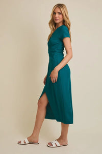Full-body of young woman in teal short sleeve surplice twist midi dress with white slide sandals