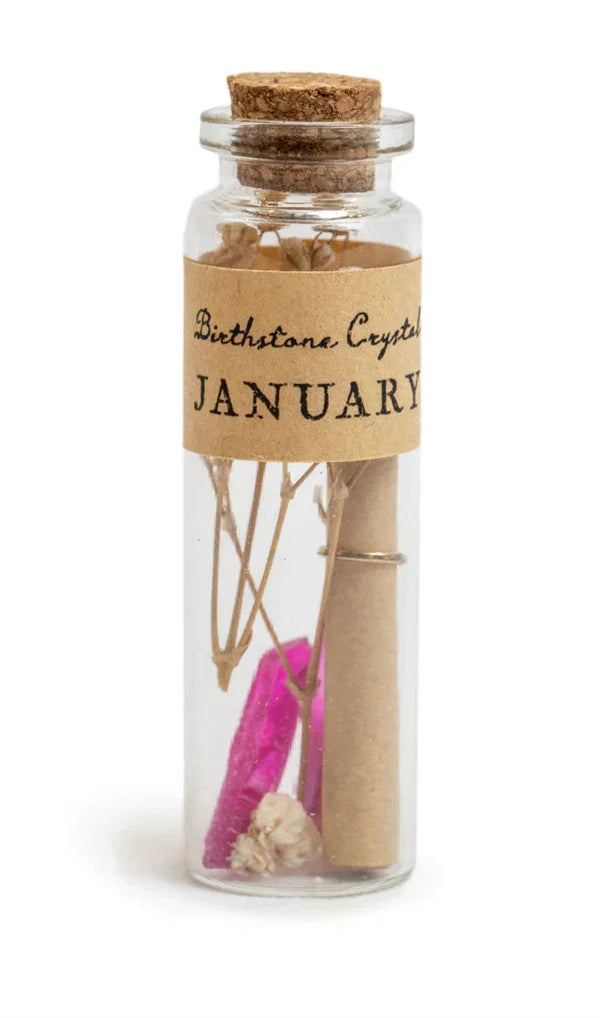 Glass bottle with dried botanicals, pink crystal, and scroll labeled Birthstone Crystal January for crystal wishing bottle