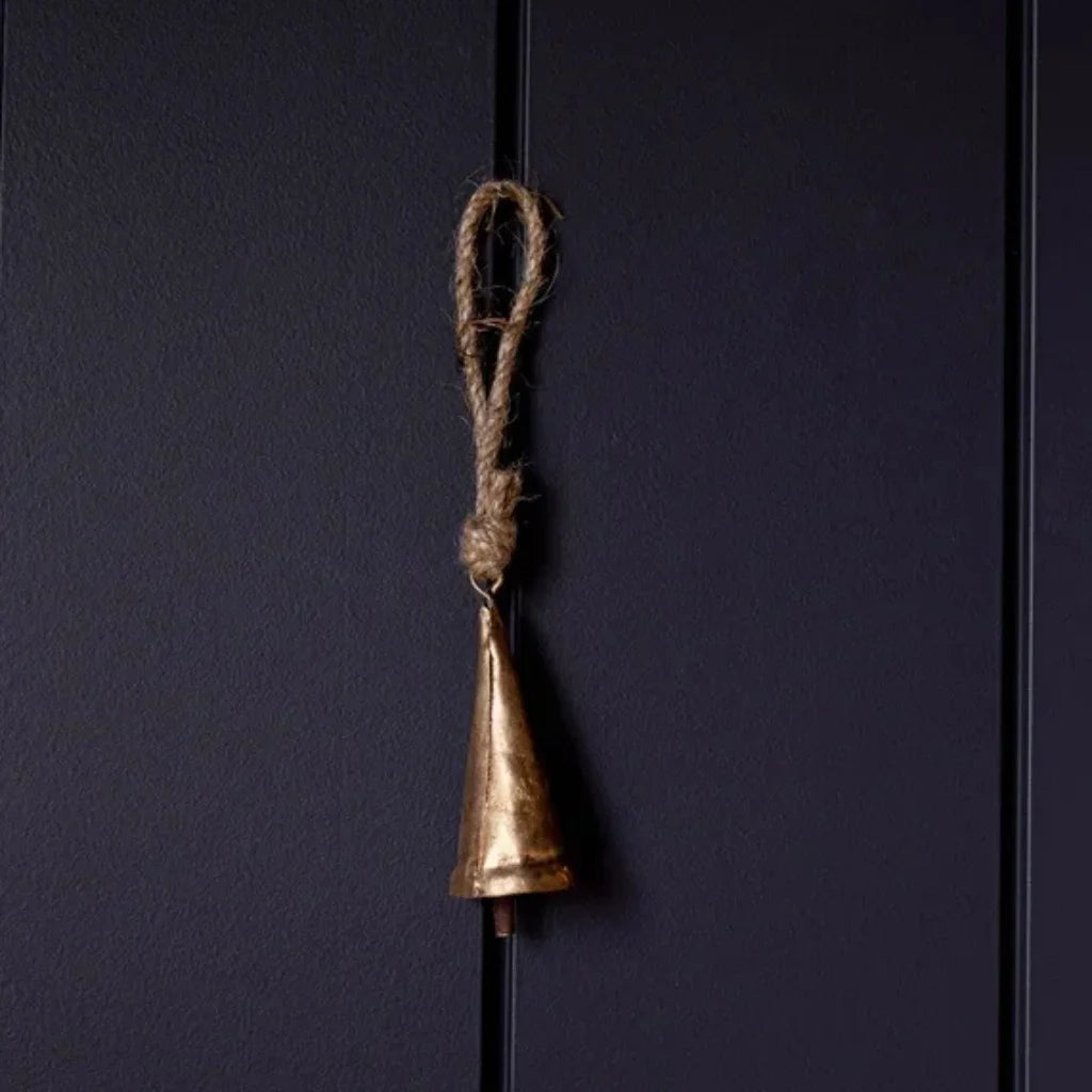 Tapered brass bell ornament with gold finish and rope handle on black background