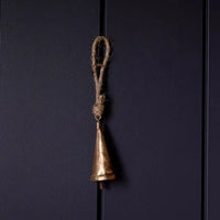 Tapered brass bell ornament with gold finish and rope handle on black background