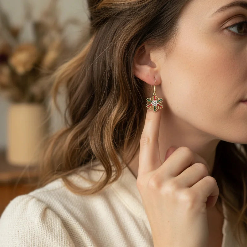 Festive rhinestone snowflake earrings with gold, green floral, and gemstone accents