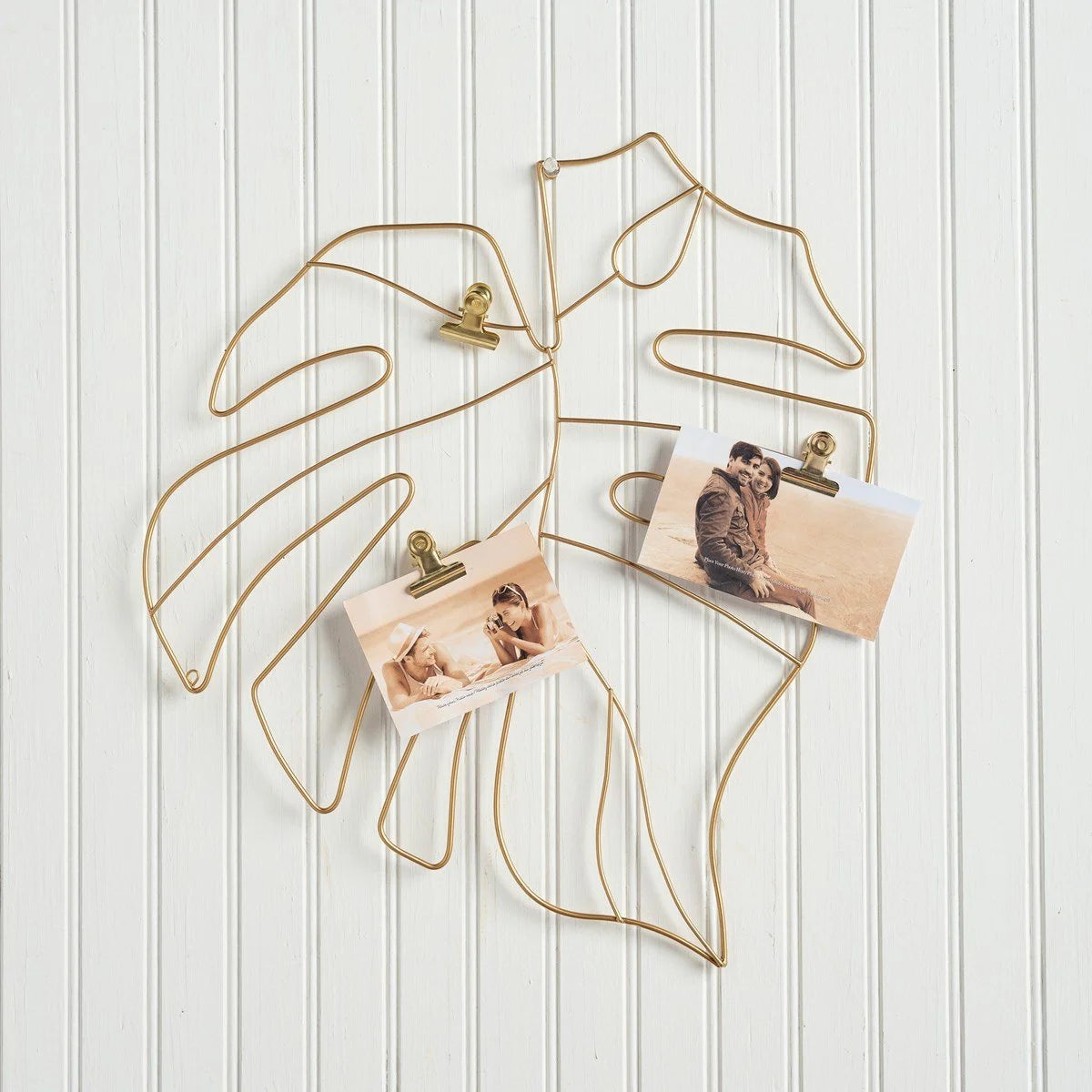 Gold metal wire photo holder featuring a Monstera leaf design with hanging photos