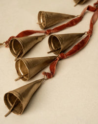 Gold metallic cone-shaped tassel garland with red velvet ribbon accents for door hanger decor